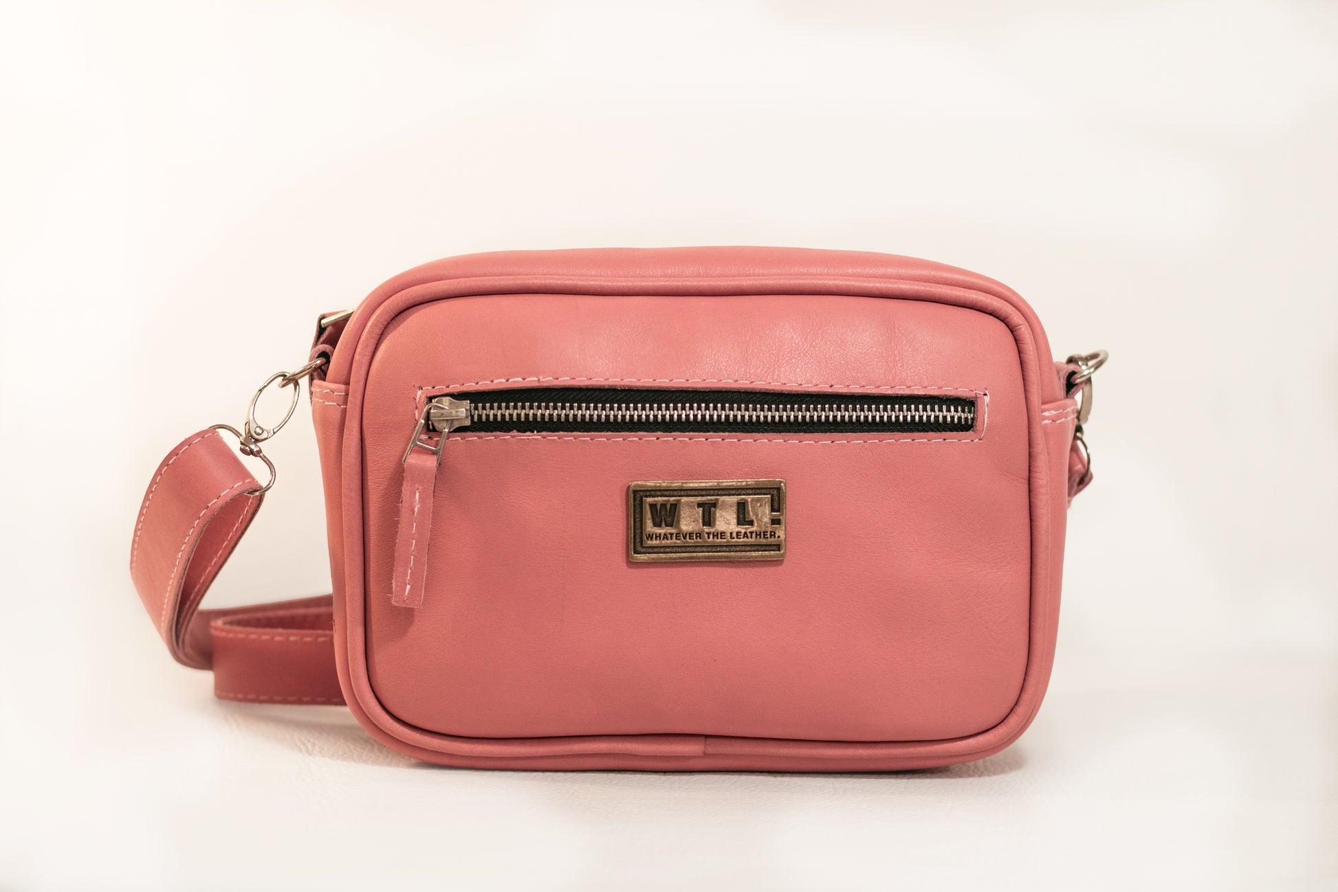 Pink crossbody bag with a visible brand logo on a white background